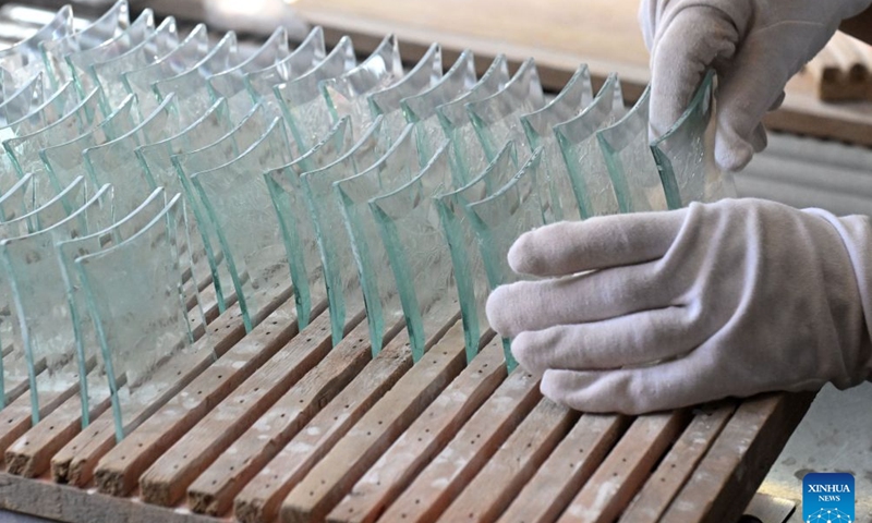 A worker arranges glass products at a glass factory in Qinhuangdao, north China's Hebei Province, Aug. 8, 2026. The city is driving the transformation and upgrading in its glass manufacturing sector, with emphasis on products for artistic creation and other special purposes. (Photo by Chen Qibao/Xinhua)