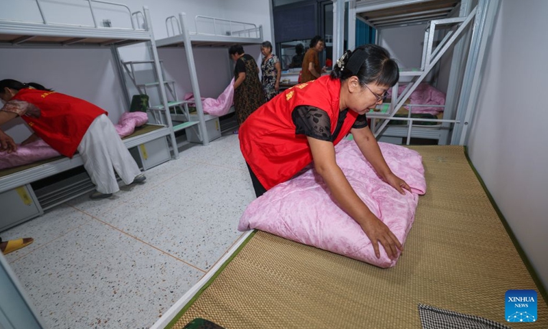 Volunteers make beds at a temporary shelter in Datian Township, Wuyi County, Jinhua City, east China's Zhejiang Province, Aug. 8, 2026.