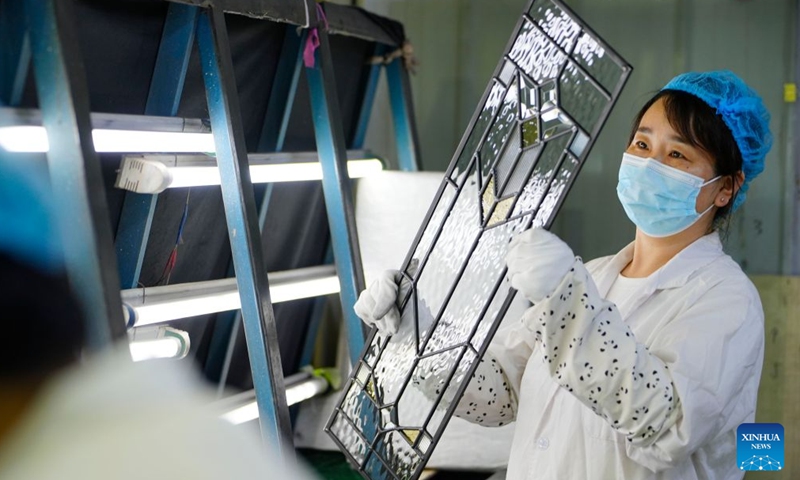 A worker examines glass products at a glass factory in Qinhuangdao, north China's Hebei Province, Aug. 8, 2026. The city is driving the transformation and upgrading in its glass manufacturing sector, with emphasis on products for artistic creation and other special purposes. (Photo by Yan Zhiguo/Xinhua)
