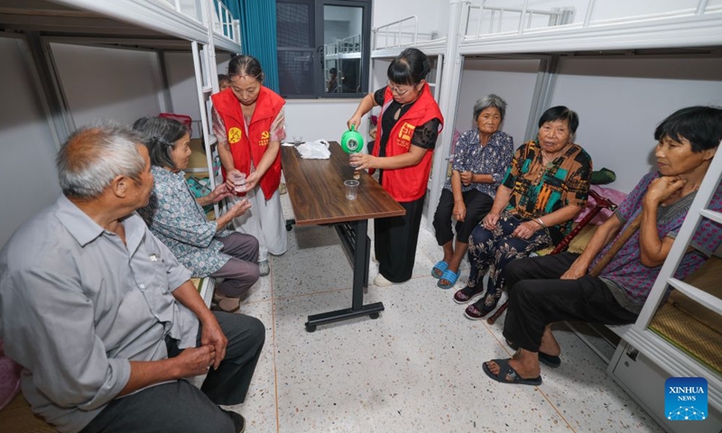 Volunteers pour drinking water for villagers at a temporary shelter in Datian Township, Wuyi County, Jinhua City, east China's Zhejiang Province, Aug. 8, 2026.