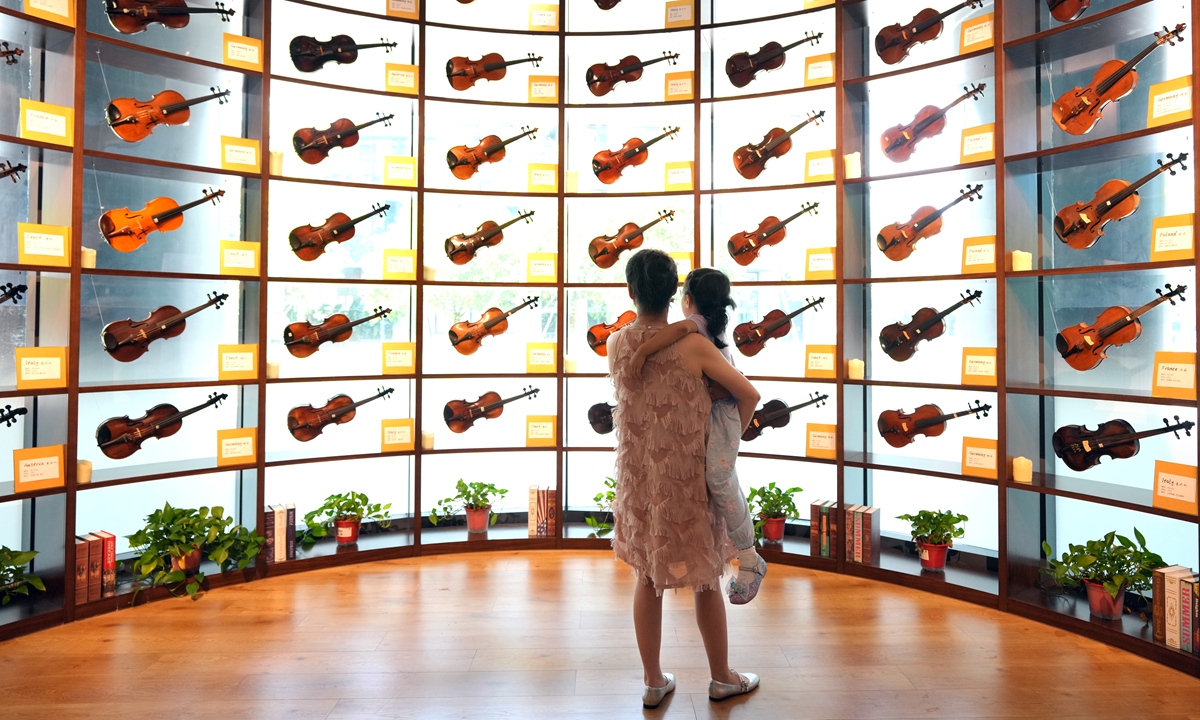 People observe the violins at a musical instrument museum in Chengdu, Southwest China's Sichuan Province, on August 9, 2026. With cutting-edge technologies, including interactive programs, 3D visuals, holographic theaters and digital scene reconstruction, the museum immerses visitors in virtual historical settings, allowing them to