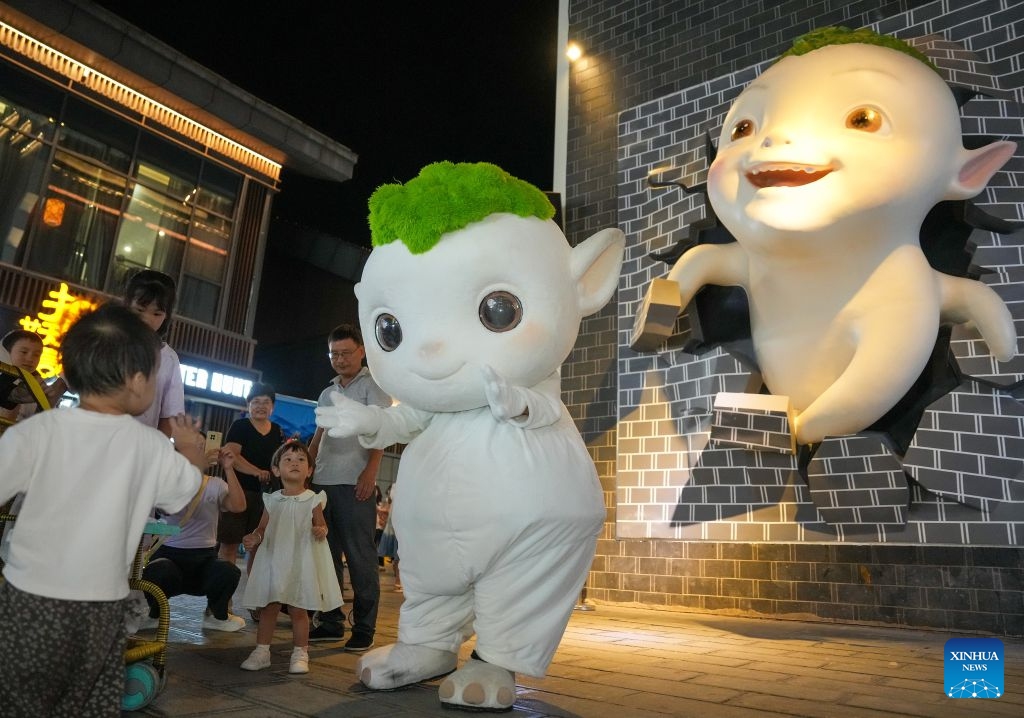 A staff member in costume interacts with children at Dayong Ancient Town in Zhangjiajie, central China's Hunan Province, Aug. 14, 2026. Leveraging its rich intangible cultural heritage, the city of Zhangjiajie has developed diverse summer getaways and multiple forms of night tours, fueling a travel boom during the peak season. (Photo: Xinhua)