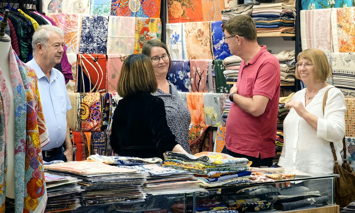 Foreign tourists explore customized clothing services at the South Bund Soft Spinning Material Market in Shanghai. Photo: VCG
