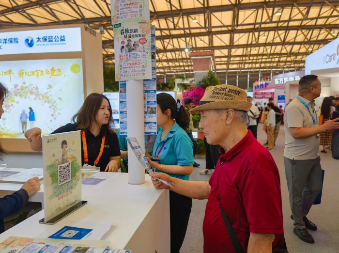 6月5日,一名老年观众在2026上海老博会上了解最新的旅游产品。新华社记者 陈爱平 摄