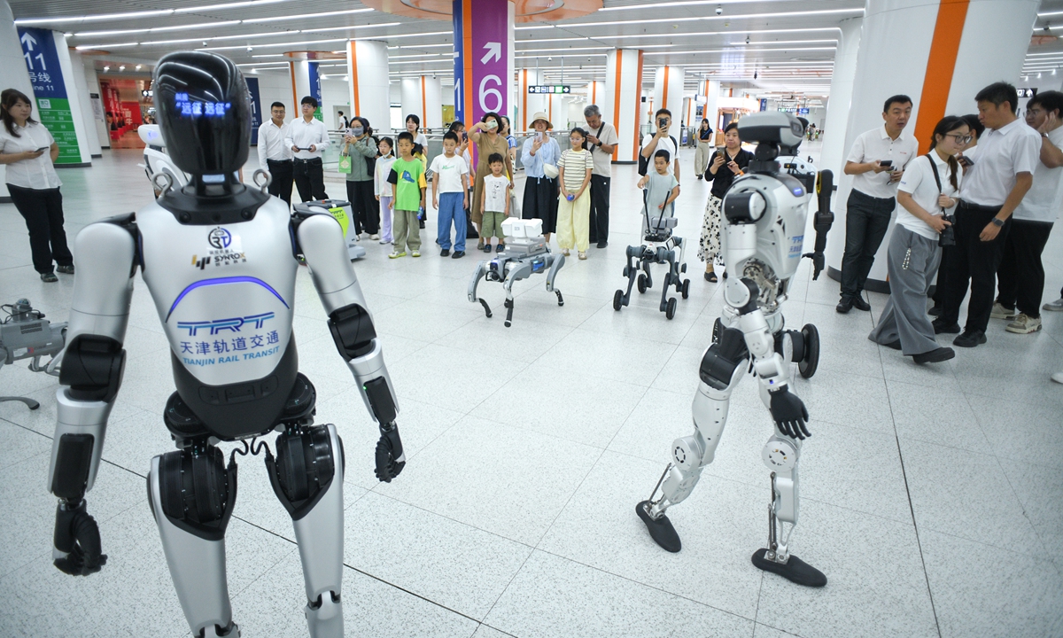 Passengers look at humanoid and quadruped robots at Tianjin Metro's Cultural Center Station on August 14, 2026 in North China's Tianjin. Tianjin Rail Transit has launched its first intelligent?robot test site, deploying over ten robots for real?scene trials across cleaning, guidance, security patrol and other scenarios. Photo: VCG