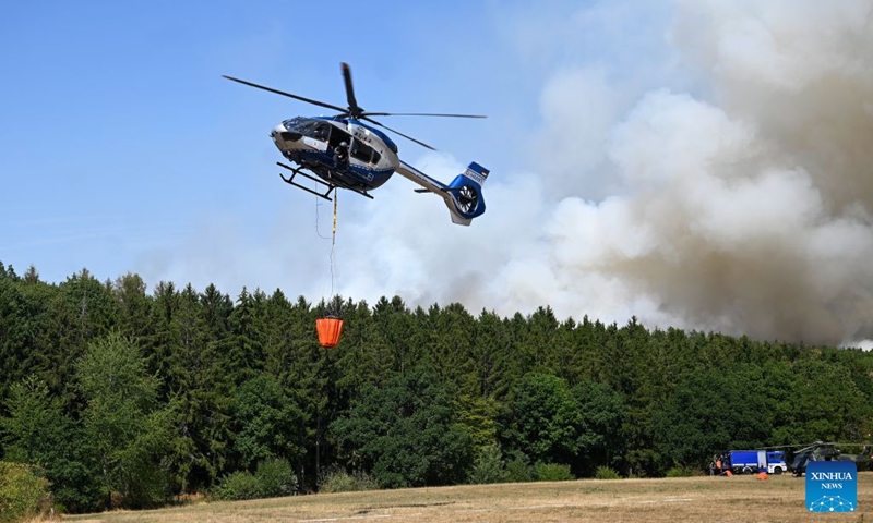 A helicopter fetches water to extinguish a wildfire in Gey, Germany, Aug. 14, 2026. According to German media reports, a wildfire broke out in North Rhine-Westphalia, and over 2,000 residents were evacuated as a precaution for safety reasons. (Photo by Ulrich Hufnagel/Xinhua)