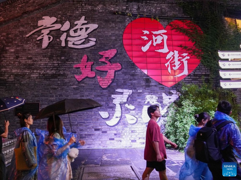 Audience move between different areas during the performance of Changde Memories, a large-scale immersive performance, at Hejie leisure district in Changde, central China's Hunan Province, on Aug. 13, 2026. Hejie is a riverside leisure district combining tourism, recreation, vacation experience and residential use. Since 2025, the district has launched Changde Memories, a large-scale immersive site-specific performance featuring light shows, the history of river transport, and stories of local intangible cultural heritage. To date, the performance has attracted more than 50,000 visits, helping boost local spending. Photo: Xinhua