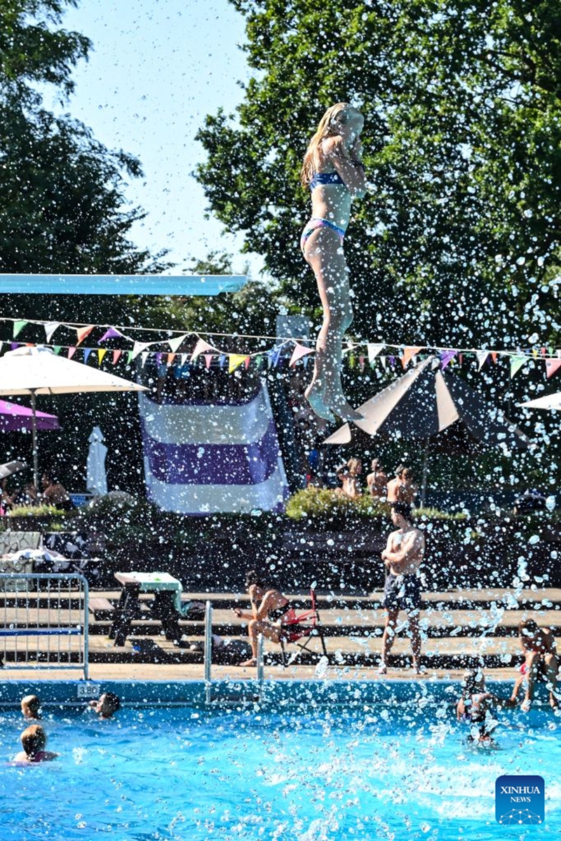 A woman jumps into an outdoor swimming pool in Delden, the Netherlands, Aug. 14, 2026. The Royal Netherlands Meteorological Institute (KNMI) issued a yellow heat warning on Aug. 14, 2026, as temperatures reached 35 degrees Celsius, marking the fifth heatwave in the Netherlands this year. (Photo by Eric Brinkhorst/Xinhua)