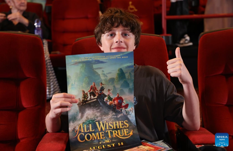 A moviegoer holds a poster for the Chinese animated film All Wishes Come True at its North American premiere in Los Angeles, California, the United States, Aug. 13, 2026. Chinese animated fantasy-comedy All Wishes Come True held its North American premiere Thursday night in Los Angeles, ahead of its theatrical release across the United States and Canada on Friday. (Photo by Zeng Hui/Xinhua)