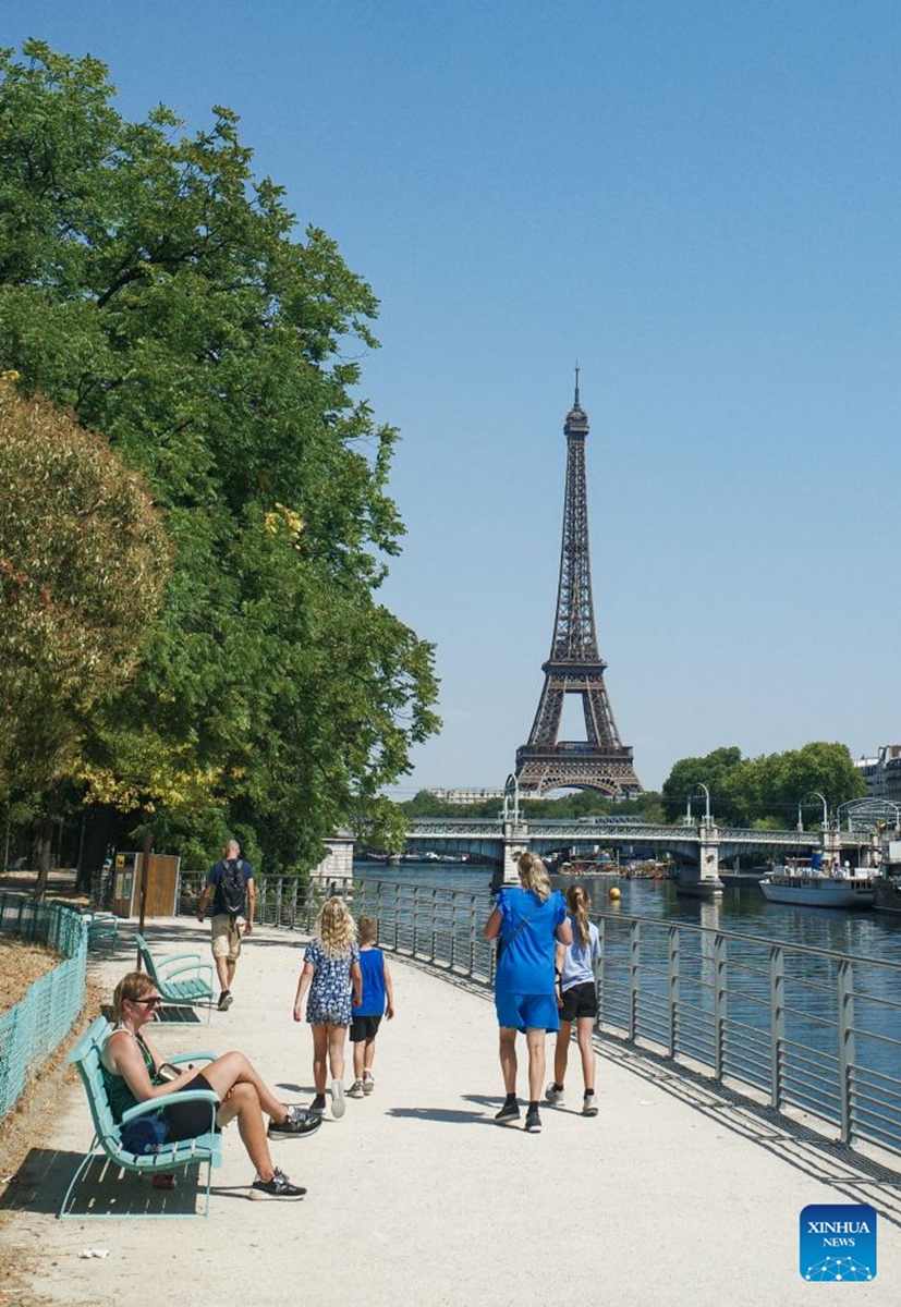 People walk in a park near the Seine River during a heatwave in Paris, France, Aug. 14, 2026. (Xinhua/Wu Huiwo)