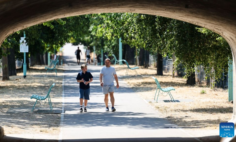 People walk in a park near the Seine River during a heatwave in Paris, France, Aug. 14, 2026. (Xinhua/Wu Huiwo)