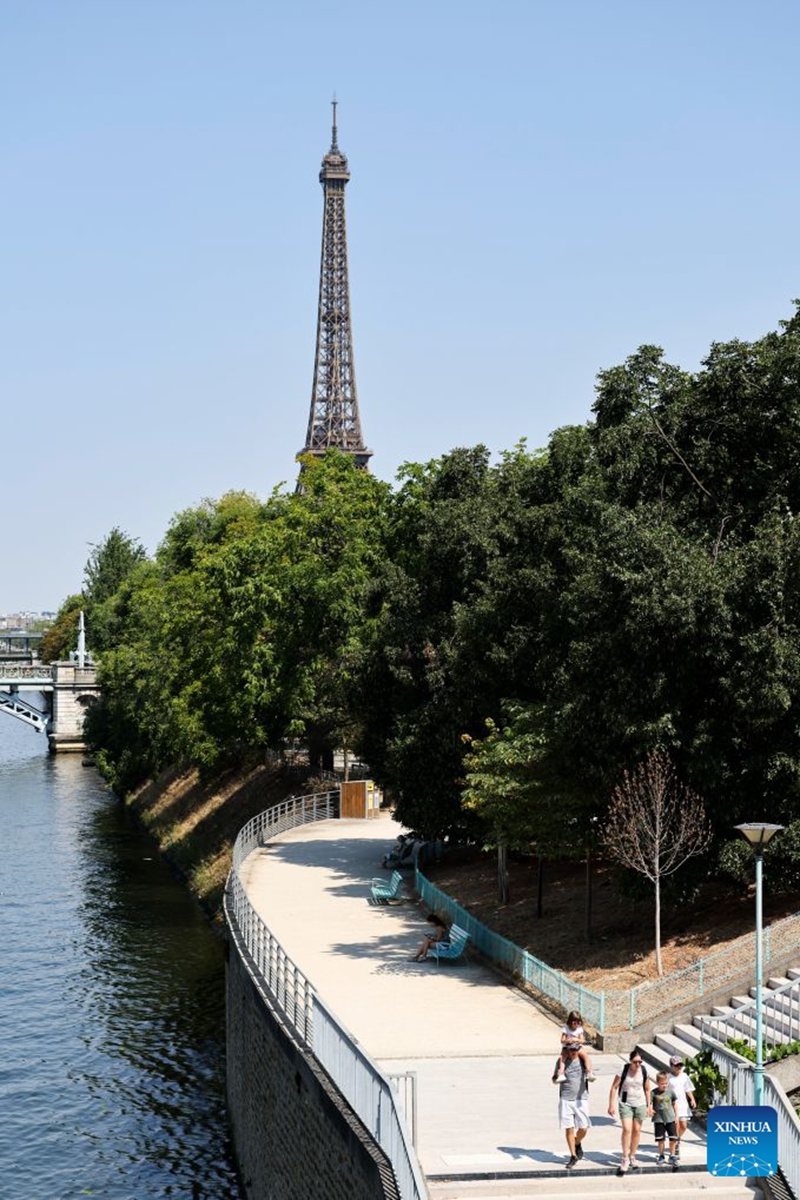 People walk in a park near the Seine River during a heatwave in Paris, France, Aug. 14, 2026. (Xinhua/Wu Huiwo)