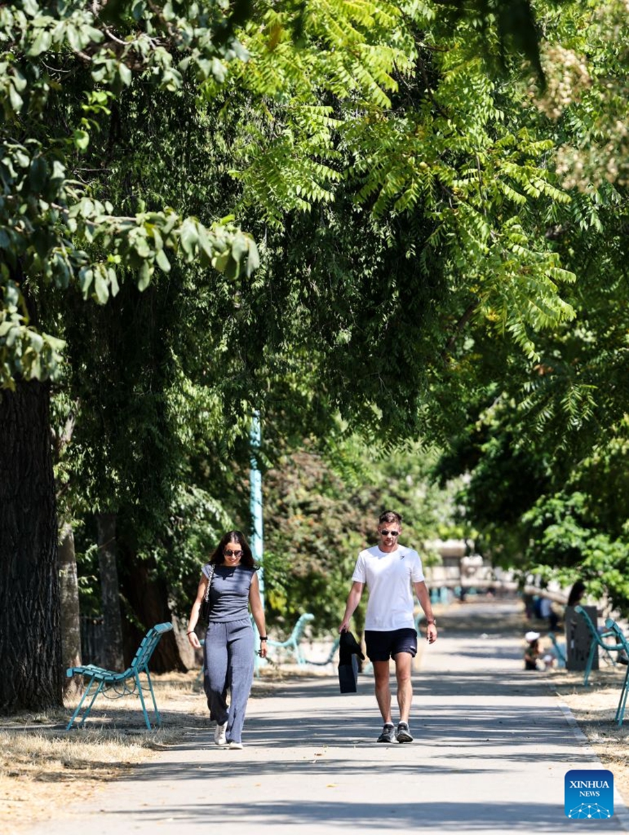 People walk in a park near the Seine River during a heatwave in Paris, France, Aug. 14, 2026. (Xinhua/Wu Huiwo)