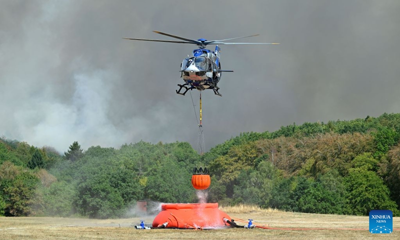 A helicopter fetches water to extinguish a wildfire in Gey, Germany, Aug. 14, 2026. According to German media reports, a wildfire broke out in North Rhine-Westphalia, and over 2,000 residents were evacuated as a precaution for safety reasons. (Photo by Ulrich Hufnagel/Xinhua)