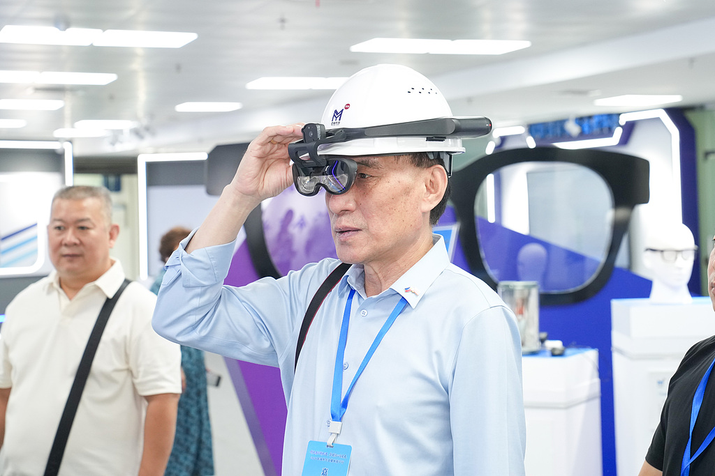 A visitor tries on AR smart glasses equipped with an intelligent inspection system. Photo: VCG