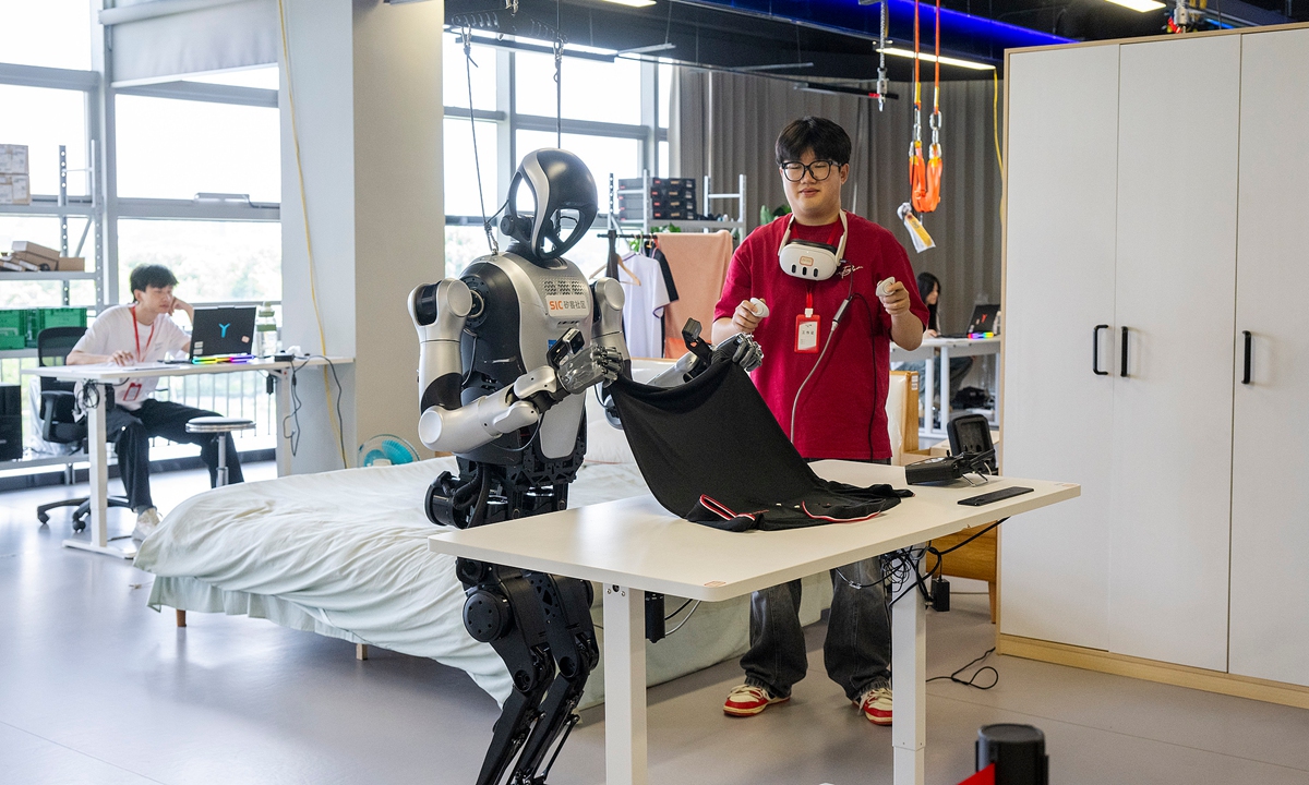A humanoid robot folds a piece of clothes under the guidance of a data collector as part of a simulated real-life setting training in Wuhu, East China's Anhui Province on August 17, 2026. Photo: VCG
