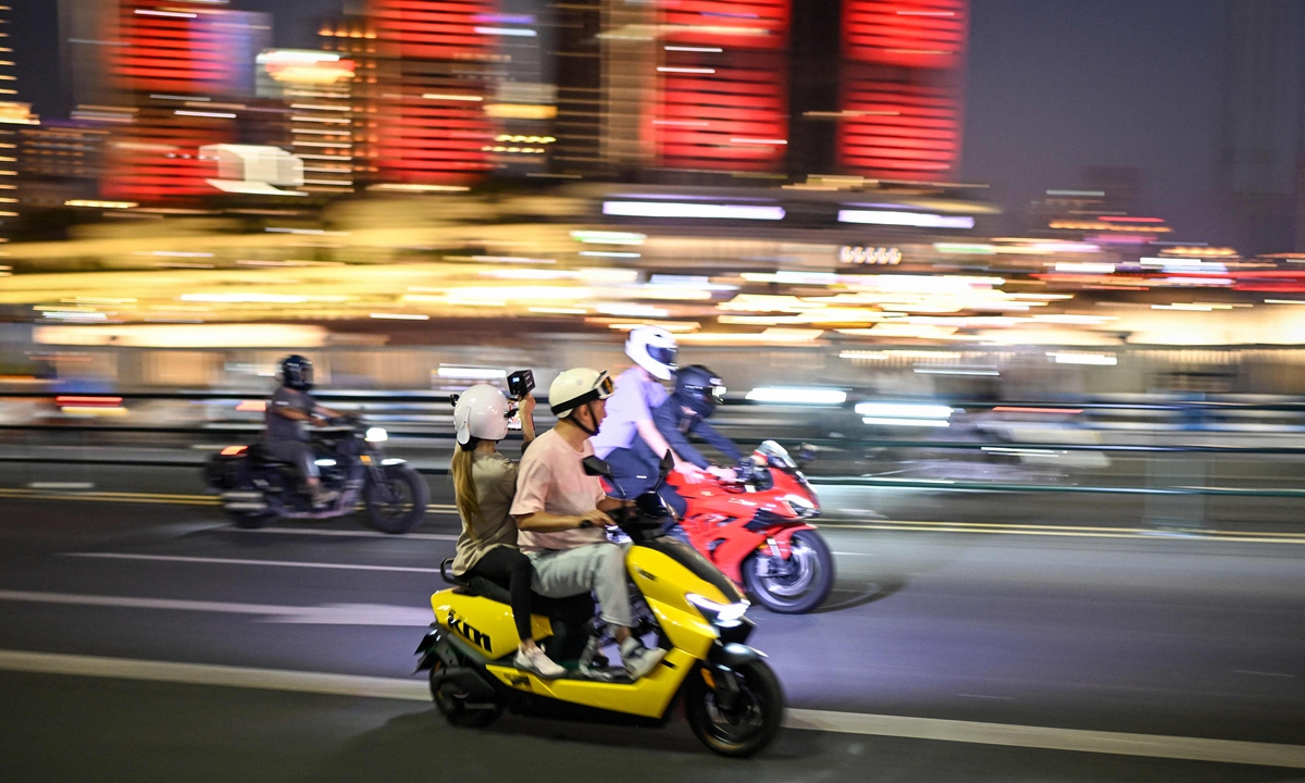 A woman films on a motorcycle in Chongqing on July 20, 2026.Photo: VCG