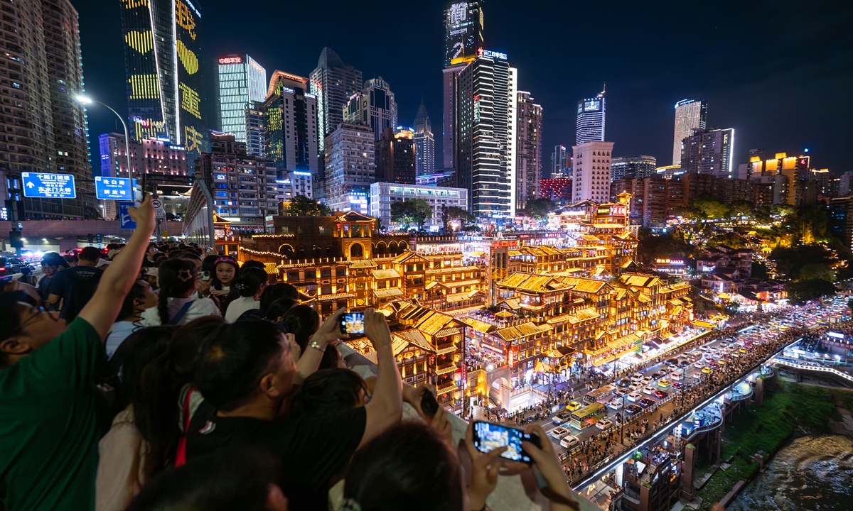 Tourists take photos against Chongqing's cityscape.Photo: VCG