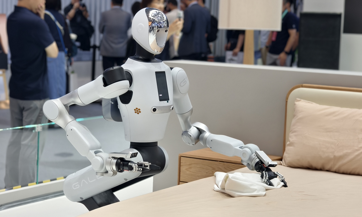 A humanoid robot folds bed linens in a bedroom setting during the 2026 World Robot Conference in Beijing on August 19, 2026. Photo: VCG