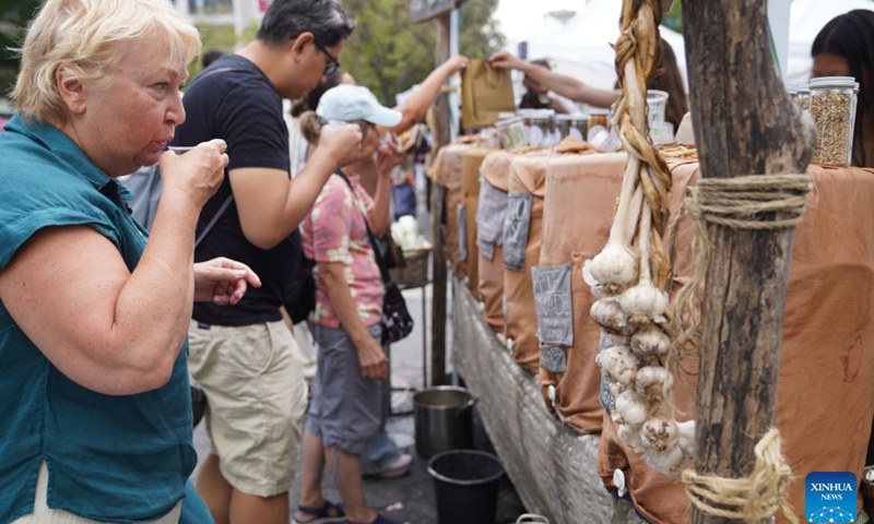 People try herbal drinks at a farmers market in New York, the United States, on Aug. 21, 2026. (Xinhua/Zhang Fengguo)