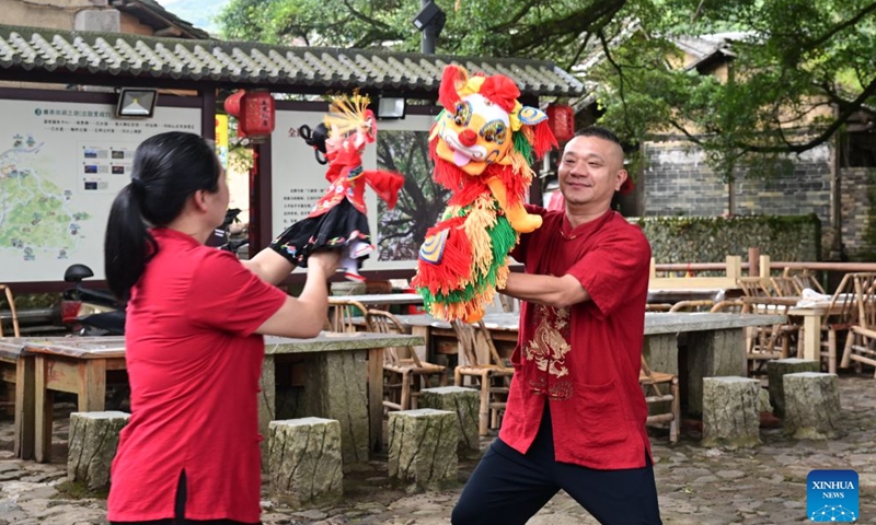 Staff members display hand puppets at the Yunshuiyao scenic spot, an ancient village known for its well-preserved Tulou compounds, in Nanjing County of Zhangzhou City, southeast China's Fujian Province, Aug. 20, 2026. In recent years, Nanjing County has been revitalizing its historical Tulou compounds and Hakka heritage by integrating culture and tourism, upgrading tourist attractions and introducing immersive experiences to draw more visitors. (Xinhua/Lin Shanchuan)
