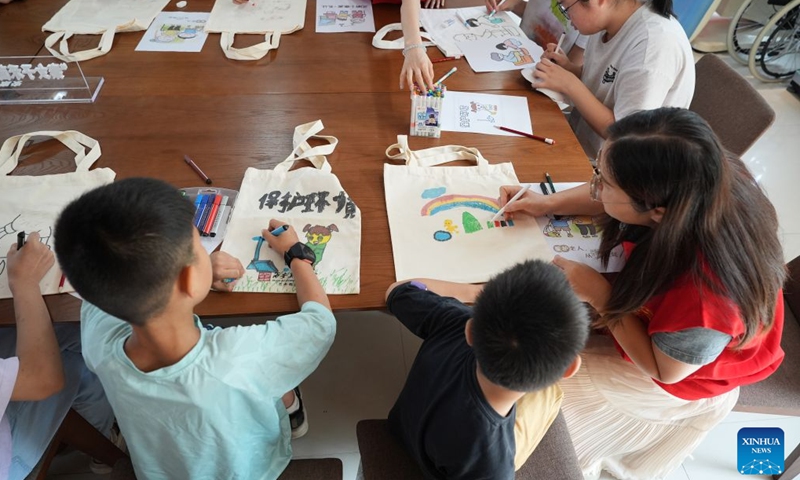 Children draw on canvas bags during a childcare program at a community in Ankang City, northwest China's Shaanxi Province, Aug. 20, 2026. In recent years, Ankang has been actively exploring new models of community service management for groups such as the elderly and children. (Xinhua/Shao Rui)