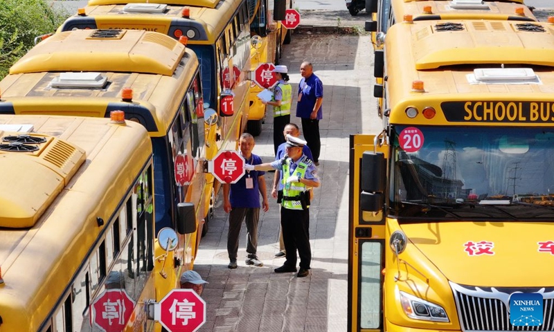 A drone photo taken on Aug. 21, 2026 shows traffic police officers inspecting school buses in Jiangxia District of Wuhan, central China's Hubei Province. Various departments across the country are getting ready for the upcoming new semester. (Photo by Zhao Jun/Xinhua)