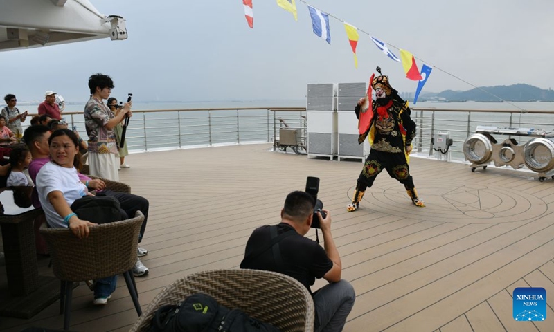 Visitors enjoy a face-changing performance aboard the cruise ship Da Wan Qu Yi Dun, Aug. 22, 2026. Named after the Greater Bay Area, known in Chinese as Da Wan Qu, the cruise ship Da Wan Qu Yi Dun departed from the Nansha International Cruise Home Port in Guangzhou on Saturday, marking the official launch of the regular Guangzhou-Shenzhen maritime cultural tourism route.
Sailing past the Hong Kong-Zhuhai-Macao Bridge, the Shenzhen-Zhongshan Link and 16 landmarks of the Greater Bay Area, the ship also provided visitors with diverse onboard experiences including performances themed on intangible cultural heritage and magic shows. Photo: Xinhua