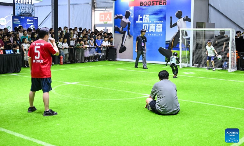 A robot takes a penalty kick as a boy plays as the goalkeeper at the 2026 World Robot Conference in Beijing, capital of China, Aug. 22, 2026. The conference, which runs from Wednesday through Sunday, has drawn more than 300 exhibitors from 26 countries, with over 3,000 products on display, including more than 300 debuts. Many people visited the conference on Saturday, the first open day of the event. Photo: Xinhua