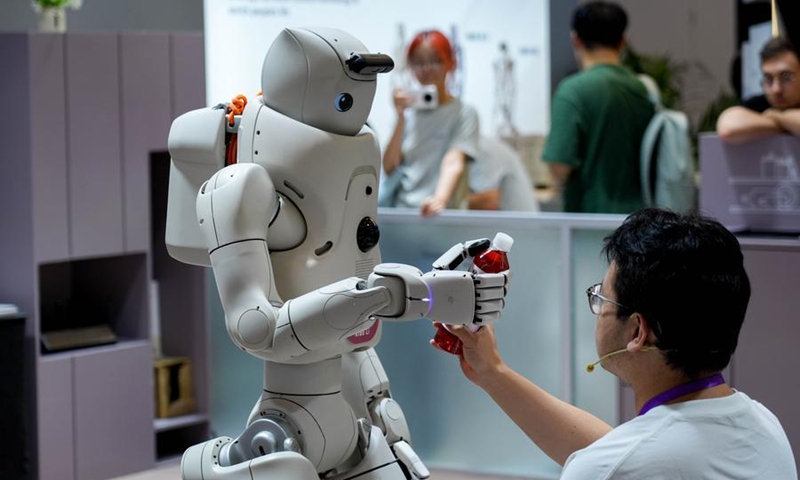 A robot gives a drink to a staff member during the 2026 World Robot Conference in Beijing, capital of China, Aug. 20, 2026. (Xinhua/Xie Han)