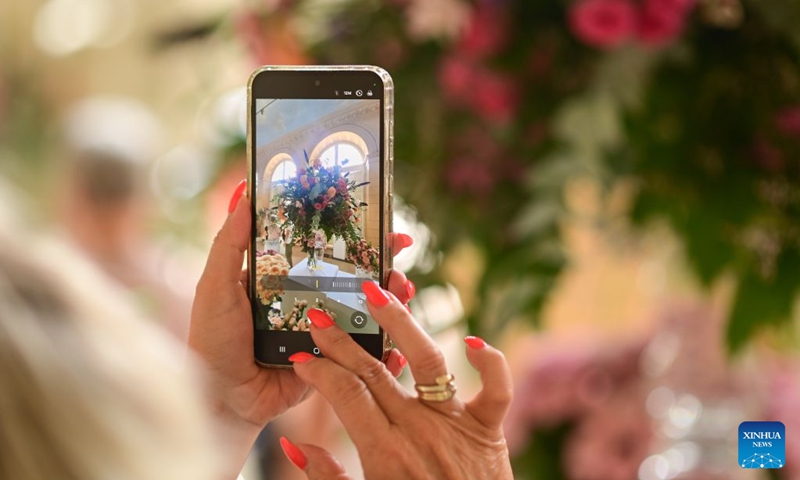 A visitor takes photos of flowers during the 42nd Royal Rose Exhibition at Royal Lazienki Park in Warsaw, Poland, on Aug. 21, 2026. The exhibition is held from Aug. 21 to 23 at Royal Lazienki Park, showcasing roses and floral arrangements from around the world. (Photo by Alexey Vitvitsky/Xinhua)