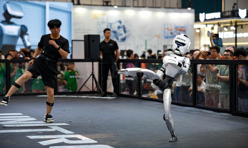 A robot and a staff member demonstrate human-robot collaboration during the 2026 World Robot Conference in Beijing, capital of China, Aug. 20, 2026. (Xinhua/Xie Han)