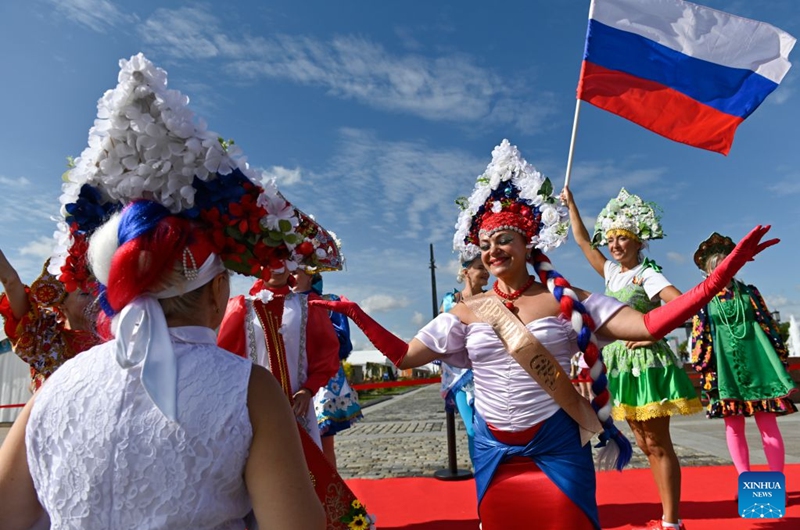 Women wearing traditional Russian headdress pose for a photo with Russian national flag at the Russian Field Art Festival at Victory Park in Moscow, Russia, on Aug. 22, 2026. The 15th Russian Field Art Festival kicked off at Victory Park in Moscow, Russia, on Aug. 22. (Photo by Alexander Zemlianichenko Jr/Xinhua)