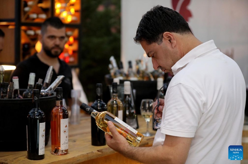 A man checks a bottle of wine at the 9th edition of the Bois de Boulogne wine festival in Bolonia village, Mount Lebanon, Lebanon, Aug. 21, 2026. (Xinhua/Bilal Jawich)