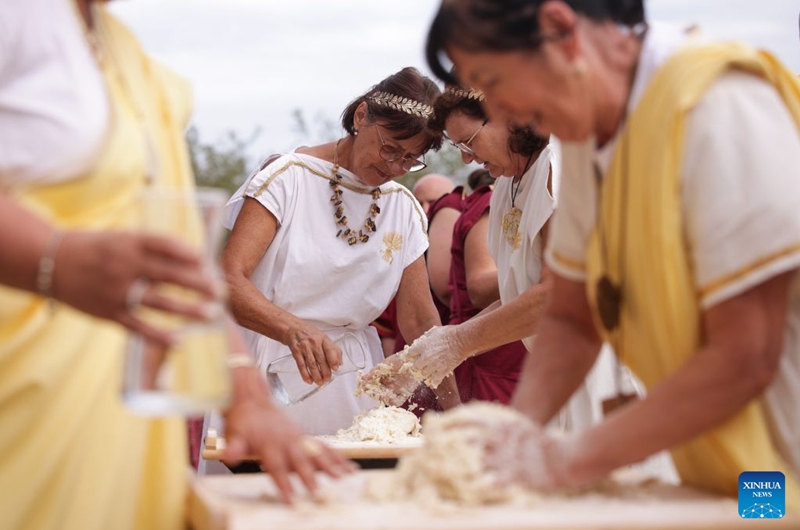 Participants dressed in Roman costumes attend a bread-making contest during the Roman Games Festival in Ptuj, Slovenia, Aug. 22, 2026. The 19th edition of the Roman Games festival kicked off on Friday in Ptuj and will last till Aug. 23. (Photo by Zeljko Stevanic/Xinhua)