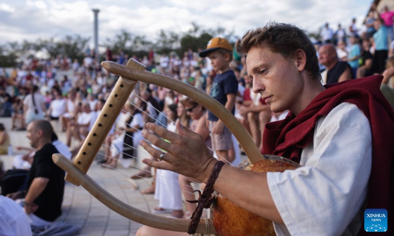 A participant dressed in Roman costume plays the lyra during the Roman Games Festival in Ptuj, Slovenia, Aug. 22, 2026. The 19th edition of the Roman Games festival kicked off on Friday in Ptuj and will last till Aug. 23. (Photo by Zeljko Stevanic/Xinhua)