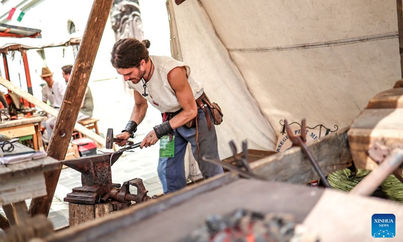 A craftsman demonstrates blacksmithing techniques during the Festival of Folk Arts at Buda Castle in Budapest, Hungary, Aug. 21, 2026. The annual festival showcases traditional Hungarian crafts and folk art as part of the celebration of Hungarian cultural heritage. (Photo by David Balogh/Xinhua)