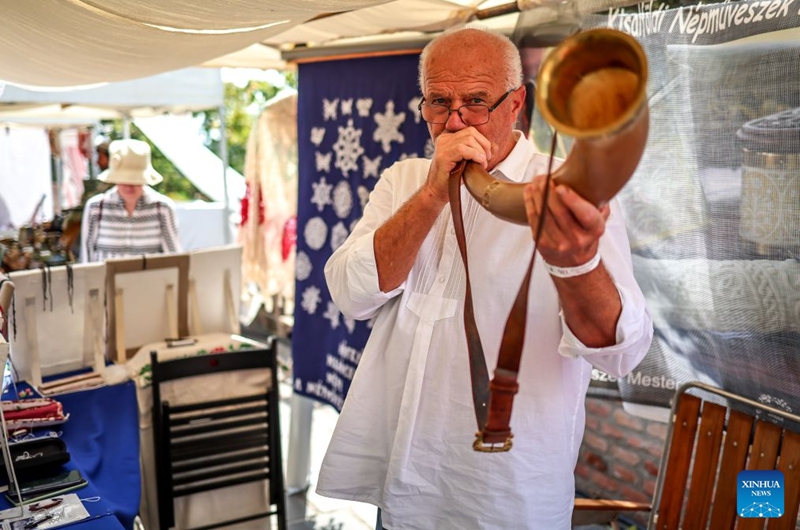 An artist plays a traditional horn during the Festival of Folk Arts at Buda Castle in Budapest, Hungary, Aug. 21, 2026. The annual festival showcases traditional Hungarian crafts and folk art as part of the celebration of Hungarian cultural heritage. (Photo by David Balogh/Xinhua)