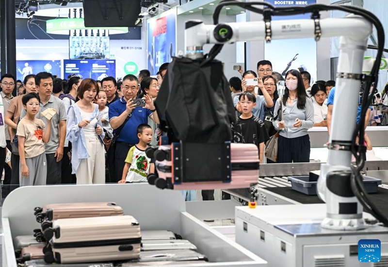 People view a robotic arm carrying a suitcase through a security screening machine at the 2026 World Robot Conference in Beijing, capital of China, Aug. 22, 2026. The conference, which runs from Wednesday through Sunday, has drawn more than 300 exhibitors from 26 countries, with over 3,000 products on display, including more than 300 debuts. Many people visited the conference on Saturday, the first open day of the event. Photo: Xinhua