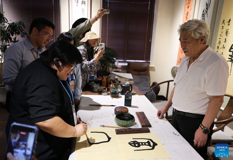 Delegates attending the Third APEC Senior Officials' Meeting and Related Meetings experience calligraphy at a historical and cultural neighborhood in Dalian, northeast China's Liaoning Province, Aug. 22, 2026. The Third APEC Senior Officials' Meeting and Related Meetings are held here from Aug. 17 to 28. (Xinhua/Li Gang)