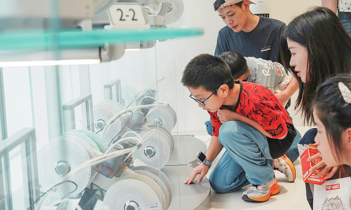 A teenager and his parents watch 3D-printed components be produced at a store in Hangzhou, East China's Zhejiang Province, on August 24, 2026. Opening that same day, this 3D-printing experience store offers consumers a complete, hands-on journey from AI modeling to 3D printing. Photo: VCG