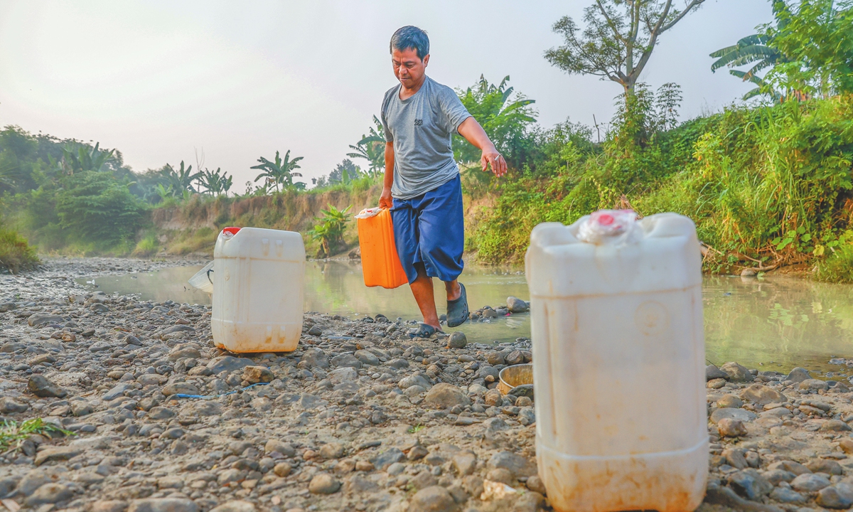 A villager carries water in a container taken from shallow wells dug into the dried-up Cihoe River in West Java, Indonesia, on August 25, 2026. Increased El Nino conditions have raised the risk of more forest and land fires during the peak dry season. Photo: VCG