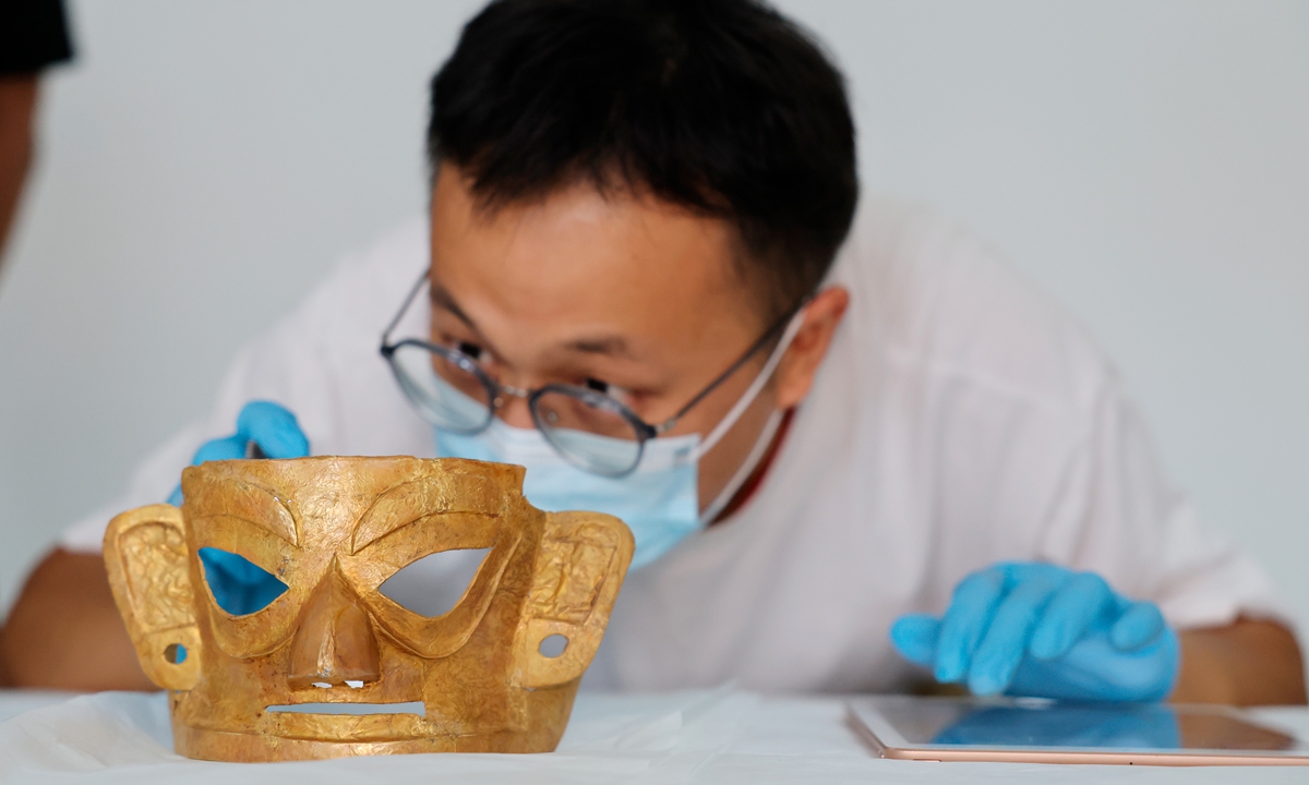 A staff member from the Jinsha Site Museum inspects a golden mask in Chengdu, Southwest China's Sichuan Province, on August 26, 2026, after the mask was returned from the National Museum of China in Beijing. A total of 108 sets of cultural relics from the Jinsha Site Museum were featured in an exhibition on the Ancient Shu civilization at the National Museum of China from January to August 2026. Photo: VCG