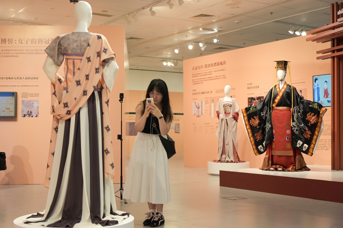 A visitor takes photos of clothing on display at an exhibition featuring Sui (581?618) and Tang (618?907) dynasties' clothing at the Hong Kong Central Library in the Hong Kong Special Administrative Region, on August 27, 2026. The exhibition offers visitors a glimpse into the profound heritage and modern innovative vitality of millennia?old clothing culture. Photo: VCG