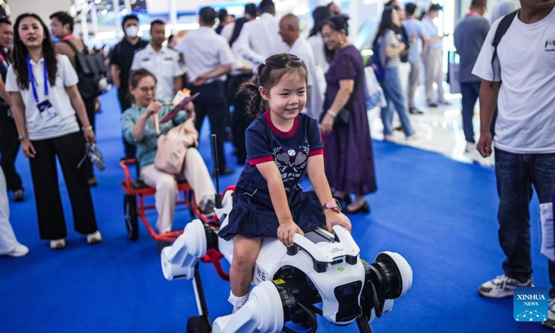 A girl tries to ride a robotic dog at the 2026 China International Big Data Industry Expo in Guiyang, southwest China's Guizhou Province, Aug. 28, 2026. The expo kicked off here on Friday, showcasing the cutting-edge technologies in several key sectors including computing power infrastructure, data supply, model-driven innovation, security safeguards, and intelligent experiences. Photo: Xinhua