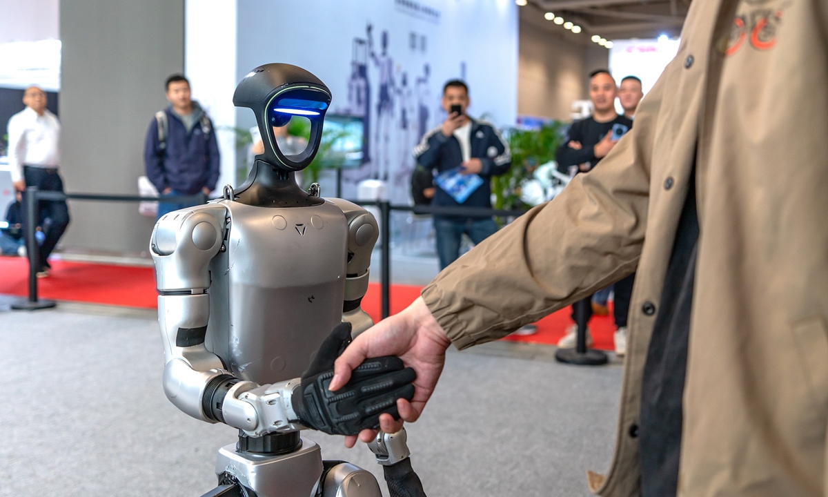 Unitree Robotics showcases a humanoid robot interacting with an audience member through a handshake.

