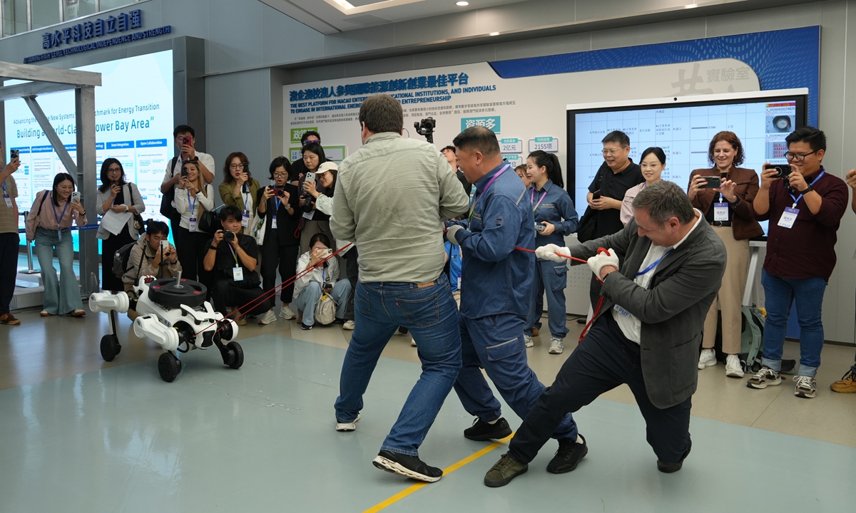 Three foreign journalists play a game of tug-of-war with a robot in Dongguan, South China's Guangdong Province, on September 3, 2026. Photo: Li Jiayu/GT