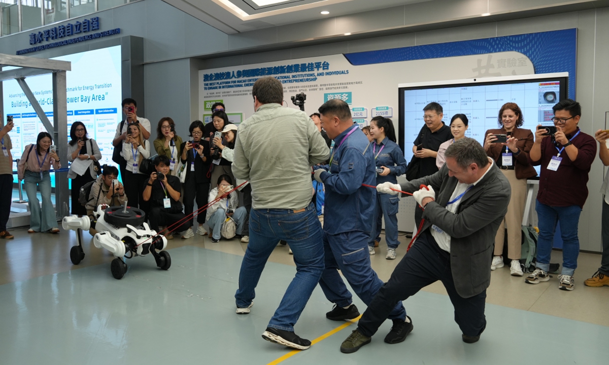 Three foreign journalists play a game of tug-of-war with a robot in Dongguan, South China's Guangdong Province, on September 3, 2026. Photo: Li Jiayu/GT