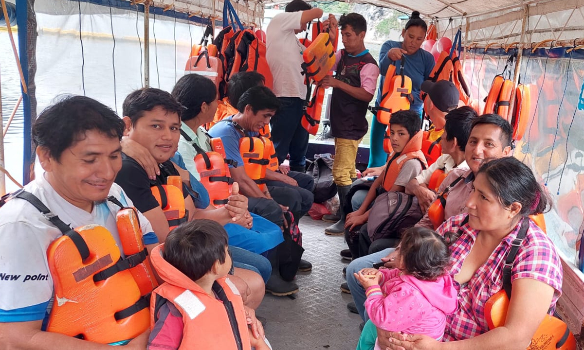 Residents, including children, travel aboard a community boat on the Chaglla Reservoir.
