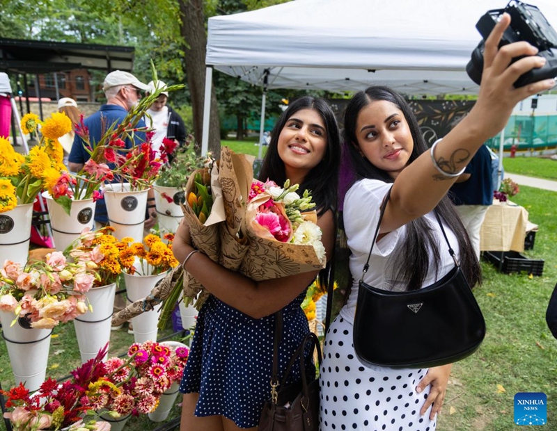 Young women pose for a selfie with flowers at the Toronto Flower Market in Toronto, Canada, on Sept. 12, 2026. The traditional monthly flower market runs here from May through October, for one day each month. (Photo by Zou Zheng/Xinhua)